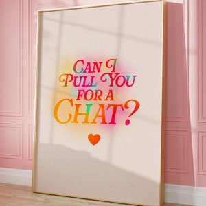 May include: A framed print with colourful, rainbow-like text overlay that reads "Can I pull you for a chat?" with a small red heart below the text. The background is a light beige with a subtle texture.