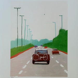 May include: A print showing a road scene with a vintage car carrying a bicycle. The artwork features a red car in the foreground, a red car in the distance, and green foliage along the roadside. The sky is a pale grey.