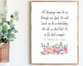 May include: A framed print with a wooden frame displays a quote by St. Teresa of Avila, accented with watercolor roses. A woven basket with greenery hangs on a white ladder, and a cream-colored blanket is draped over the ladder.