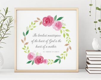 May include: A framed print with a gold border features a watercolor floral wreath in shades of pink, green, and brown. The text reads, "The loveliest masterpiece of the heart of God is the heart of a mother." Signed, "ST. THERESE OF LISIEUX."