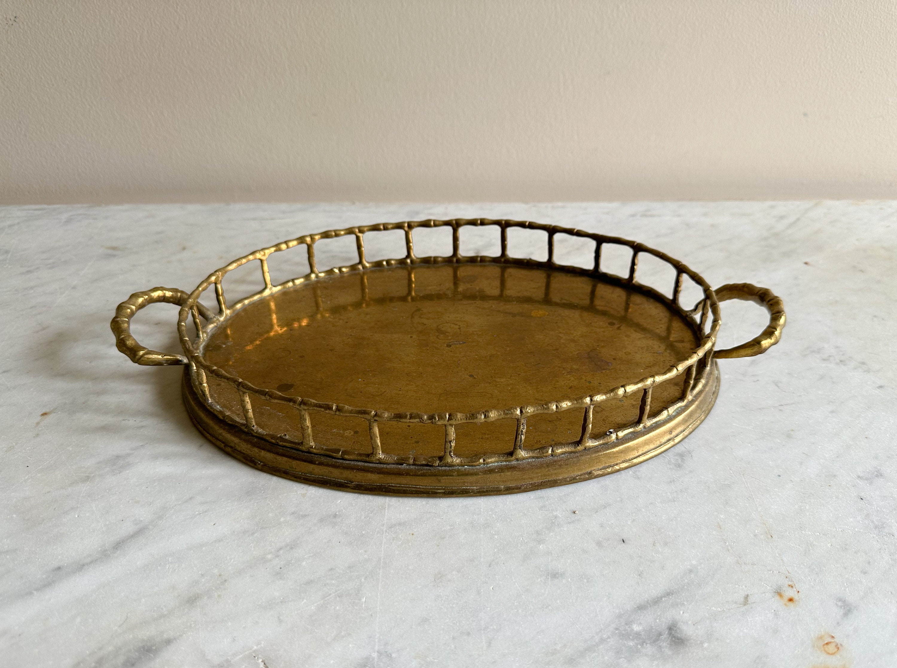 This hand-crafted oval brass tray, featuring a faux bamboo brass