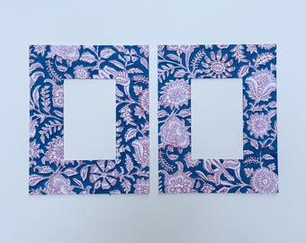 May include: Two blue picture frames with a white floral pattern and a red outline. The frames have a white rectangular opening in the center.