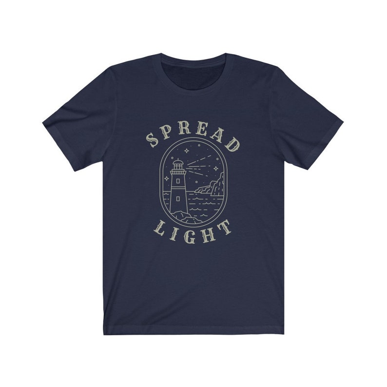 Op de afbeelding: Donkerblauw T-shirt met een vuurtorenafbeelding en de tekst "SPREAD LIGHT" in een vintage-ge&iuml;nspireerd lettertype.