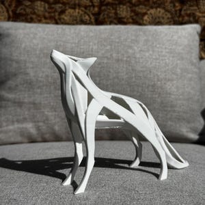 May include: A white, stylized sculpture of a howling wolf. The sculpture is made of interconnected, linear elements, creating an open, airy design. The wolf is depicted in a standing position with its head raised, set against a neutral background.