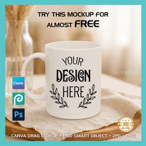 May include: White ceramic mug with the text "YOUR DESIGN HERE" in a black, bold font, with a decorative leaf design. The mug is on a wooden surface with text that says "TRY THIS MOCKUP FOR ALMOST FREE".