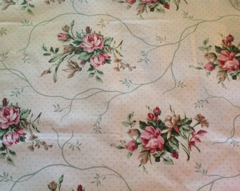 May include: A white fabric with a repeating pattern of pink roses and green leaves on a white background with small pink dots.