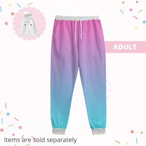 Könnte beinhalten: Erwachsene Jogginghose mit Farbverlauf von Rosa zu Blau. Die Hose hat einen weißen Kordelzug und Bündchen mit einem bunten Streusel-Muster. Ein passender Einhorn-Hoodie ist oben links abgebildet. Der Text "ADULT" ist sichtbar.