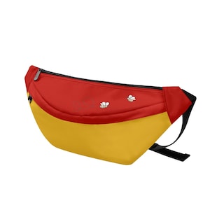 May include: A red and yellow fanny pack with a black zipper and strap. The top section is red, and the bottom is yellow. Two small bee graphics are on the red section. The fanny pack is designed to be worn around the waist.
