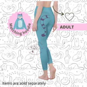 May include: Light blue leggings featuring a purple and white striped tail design. The leggings are part of a set, with a matching blue hoodie with cat ears. The background has a white pattern of cat illustrations. The word "ADULT" is displayed.