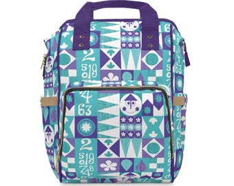 May include: A colorful backpack with a geometric pattern in teal, purple, and white. The design includes numbers, stylized faces, and floral shapes. It has a purple handle and trim, with tan side pockets.