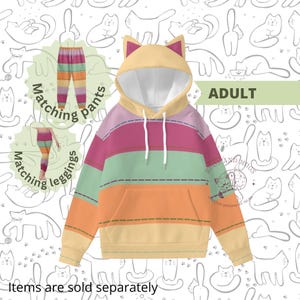 Könnte beinhalten: Ein farbenfroher Hoodie mit Katzenmotiv und eine passende Hose und Leggings. Der Hoodie hat eine Katzenohrenkapuze, eine Vordertasche und horizontale Streifen in Rosa, Grün, Orange und Gelb. Der Text "ADULT" ist sichtbar. Artikel werden separat verkauft.