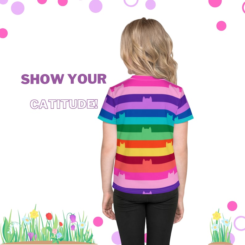 May include: A child wearing a rainbow striped t-shirt with black cat silhouettes. The shirt says "Show Your Cattitude!"