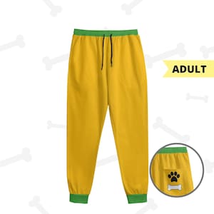 May include: Yellow adult sweatpants with a green waistband and cuffs. The sweatpants have a drawstring and two pockets. A small inset shows a pocket with a paw print and bone graphic.