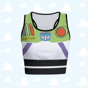 Puede incluir: Un top corto verde, blanco y negro con un diseño inspirado en el personaje Buzz Lightyear. La parte superior presenta las palabras "LIGHTYEAR" y "SPACE RANGERS" junto con otros elementos gráficos. La parte superior tiene un estilo de espalda deportiva.