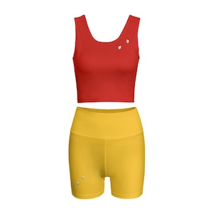 Può includere: Un completo sportivo composto da un top corto rosso e pantaloncini gialli. Il top corto ha uno scollo tondo e piccoli abbellimenti floreali. Gli shorts a vita alta sono di un giallo vibrante. Ideale per allenamenti o abbigliamento casual.