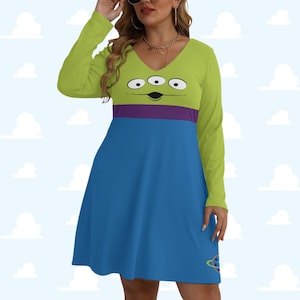 Può includere: Abito a maniche lunghe con un design alieno dei cartoni animati. La parte superiore è verde lime con tre occhi e una bocca nera, separata da una striscia viola dalla gonna blu. Una grafica del pianeta è sulla gonna.