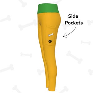 May include: Mustard yellow leggings with a green waistband. A side pocket features a white bone and a black paw print. The text "Side Pockets" is next to the leggings.