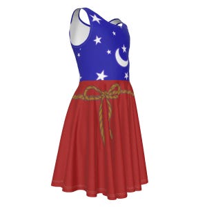 May include: A sleeveless skater dress with a blue bodice decorated with white stars and a crescent moon. The red skirt has a brown rope bow detail. The dress is made of a soft, flowing fabric.