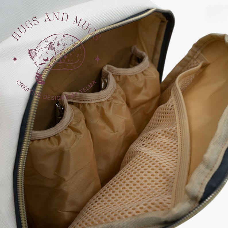 Peut inclure: Int&eacute;rieur d'un sac &agrave; dos blanc et bleu marine avec plusieurs compartiments. L'int&eacute;rieur comprend trois poches en tissu beige et une poche en filet. Le sac &agrave; dos a une fermeture &eacute;clair dor&eacute;e et un logo avec un chat endormi et le texte "Hugs and Mugs, Creative Design by Telma."