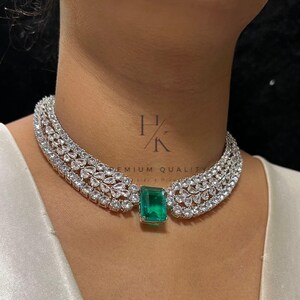 Puede incluir: Un lujoso collar gargantilla con un gran colgante rectangular de esmeralda. El collar est&aacute; adornado con numerosas piedras claras y brillantes. El dise&ntilde;o es elegante y llamativo, perfecto para ocasiones especiales.
