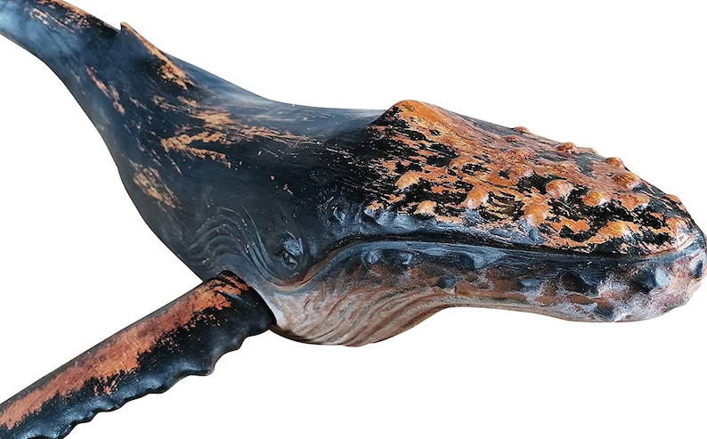 May include: A wooden whale sculpture with a distressed black and brown paint finish. The whale is carved in detail and has a realistic appearance.