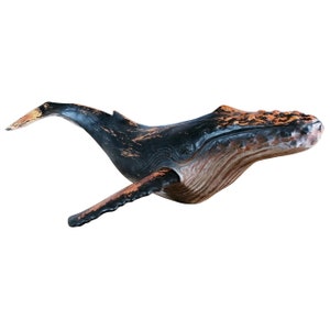 May include: A black and brown wooden whale sculpture with a distressed finish. The whale is in a swimming position with its mouth open.