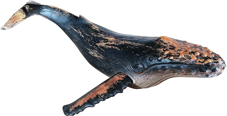 May include: A wooden whale sculpture with a black and brown distressed paint finish. The whale is in a swimming position with its tail and fin raised.