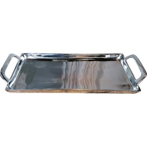 Può includere: Un vassoio da portata rettangolare argentato con due manici. Il vassoio è in metallo e ha una superficie liscia e lucida.
