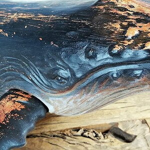 May include: A black and copper whale sculpture with a distressed finish. The whale has a carved design on its body and a tail fin.