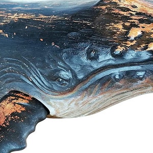 May include: Close-up of a wooden whale sculpture with a distressed black and copper paint finish. The whale's eye and mouth are carved into the wood, and the tail fin is partially visible.