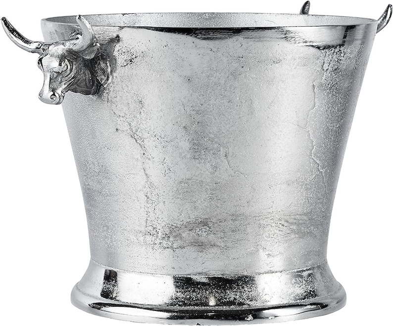 May include: Silver ice bucket with bull head handles. The bucket has a textured surface and a wide base.