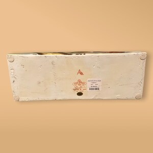 May include: White ceramic rectangular serving tray with a colorful floral design. The tray has a label on the bottom that reads "Anthropologie" and "John Derian" with a price tag of $150.00.