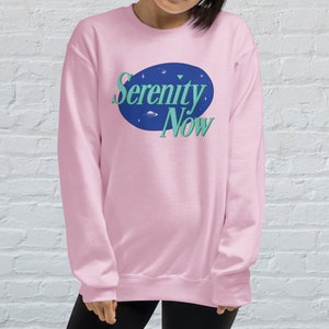 May include: Pink sweatshirt with a blue and green logo that says "Serenity Now".