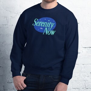 May include: A navy blue sweatshirt with a blue and green logo that says "Serenity Now" in a white circle.