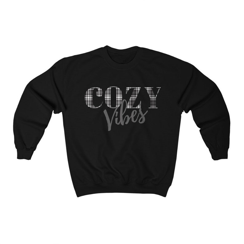 May include: Black sweatshirt with the words "COZY Vibes" printed on the front. The word "COZY" is in a plaid pattern, and "Vibes" is in a cursive font. The sweatshirt is a crew neck style.
