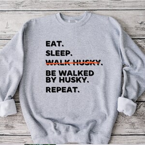 May include: Gray sweatshirt with black text that reads "Eat. Sleep. Walk Husky. Be walked by Husky. Repeat."