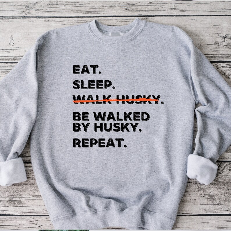 May include: Gray sweatshirt with black text that reads "Eat. Sleep. Walk Husky. Be walked by Husky. Repeat."