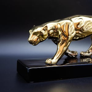 A Ceramic Golden Panther on a Black Pedestal in a Walking Pose Ideal as an Eye-Catcher in the Living Room or as a Gift for Cat Lovers