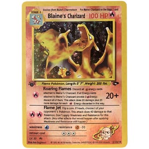 May include: A vintage Blaine's Charizard Pokémon card. The card features a fiery orange Charizard illustration with the text "Blaine's Charizard 100 HP". The card has a Stage 2 designation and includes attack details and stats.