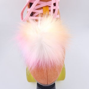 Pu&ograve; includere: Un paio di pattini a rotelle con un pon pon di pelliccia rosa e bianco sulla punta dello stivale.