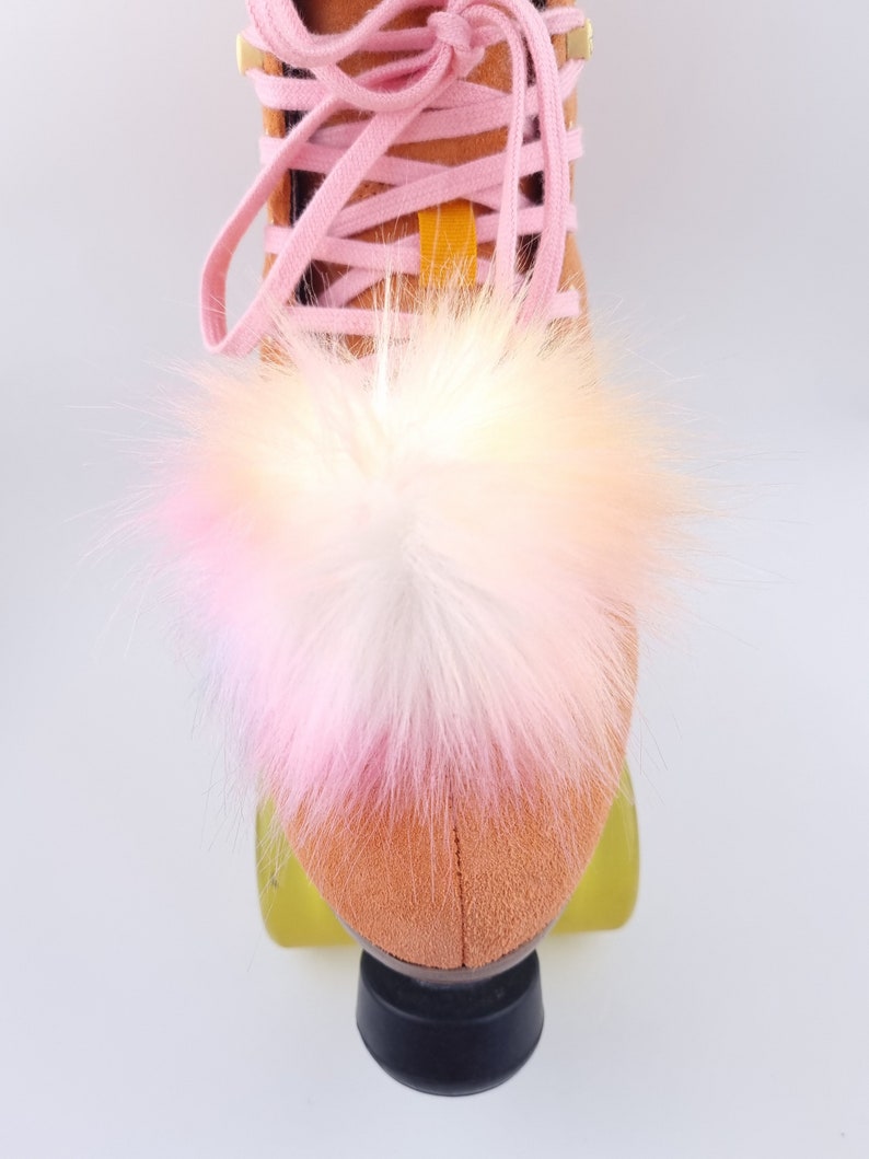 Pu&ograve; includere: Un paio di pattini a rotelle con un pon pon di pelliccia rosa e bianco sulla punta dello stivale.