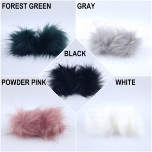 Pu&ograve; includere: Cinque pompon in pelliccia sintetica di diversi colori: verde bosco, grigio, nero, rosa cipria e bianco. I pompon sono disposti a griglia.