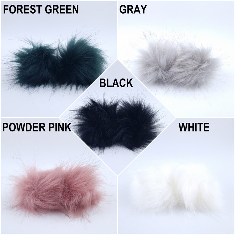 Pu&ograve; includere: Cinque pompon in pelliccia sintetica di diversi colori: verde bosco, grigio, nero, rosa cipria e bianco. I pompon sono disposti a griglia.