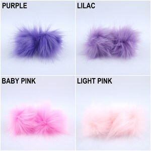 Pu&ograve; includere: Quattro pompon in pelliccia sintetica di diversi colori: viola, lilla, rosa tenue e rosa chiaro. I pompon sono disposti in una griglia.