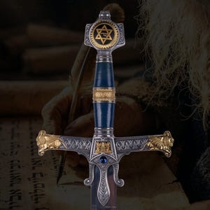 May include: A decorative sword featuring a blue handle with gold accents, a silver crossguard with gold lion heads on each end, and a central blue gemstone. The pommel displays a gold Star of David with Hebrew text inside a circular frame.