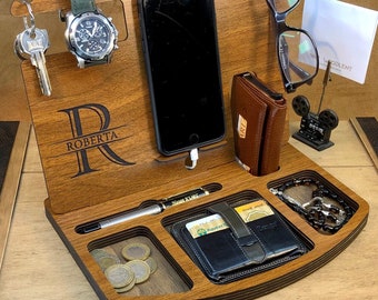 Può includere: Un organizzatore in legno con scomparti per un telefono, un orologio, chiavi, un portafoglio e altri oggetti. L'organizzatore ha un'iscrizione personalizzata che dice "Roberta".