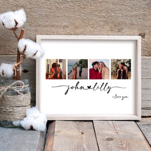May include: A rectangular wooden frame containing a white print with four square photographs of a couple, the names "john" and "lilly" connected by a heart, and the text "i love you" in black script, next to a glass jar with cotton stems.