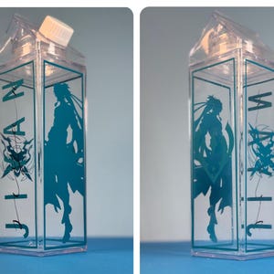 May include: Clear plastic milk carton-shaped water bottle with a teal graphic of a character and the word "JIA" in teal. The bottle has a white cap and is displayed against a blue background.