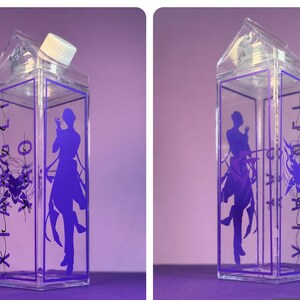 May include: Clear, rectangular water bottle with a purple design. The bottle has a white cap and a purple silhouette of a person on the front. The sides feature purple text and a graphic design. The bottle is on a purple surface.