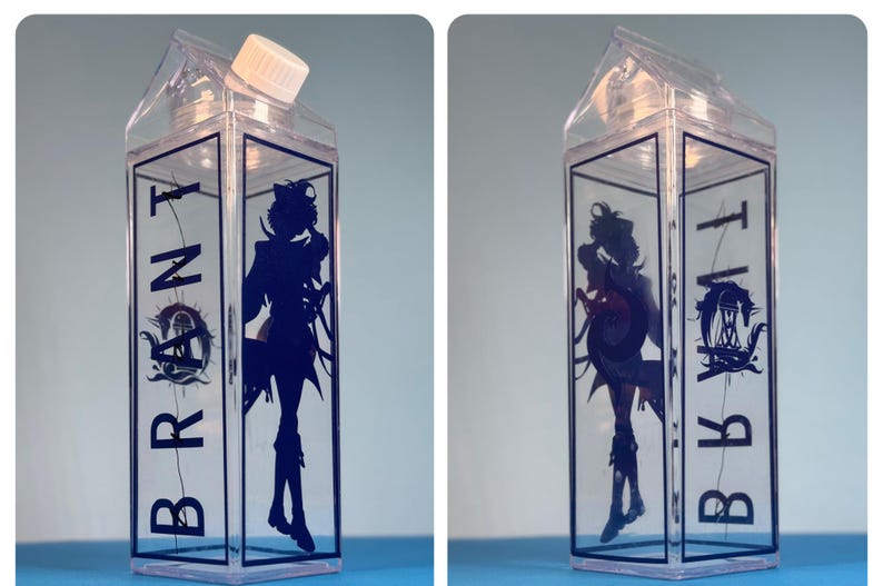 May include: Clear plastic water bottle with a white cap, shaped like a milk carton. The bottle features a dark blue silhouette of a character and the word "BRONT" in dark blue.